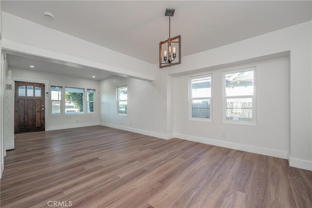 unfurnished living room featuring hardwood / wood-style floors and an inviting chandelier