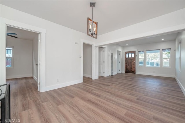 unfurnished living room featuring a chandelier, recessed lighting, light wood-style flooring, and baseboards