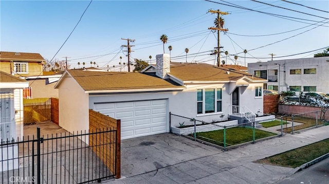 view of front of house with a garage, driveway, a fenced front yard, and stucco siding