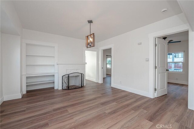 unfurnished living room with an inviting chandelier, wood-type flooring, and a fireplace