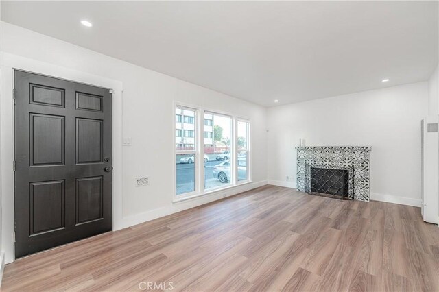 unfurnished living room with a tile fireplace and light hardwood / wood-style flooring