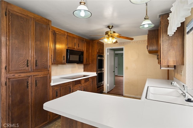 kitchen featuring black appliances, sink, hanging light fixtures, ceiling fan, and kitchen peninsula