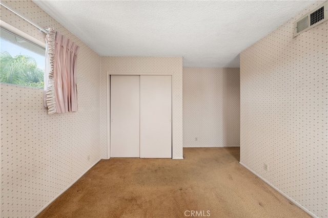 unfurnished bedroom with a closet, a textured ceiling, and carpet flooring