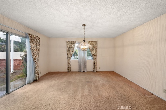 carpeted spare room with a textured ceiling and a chandelier