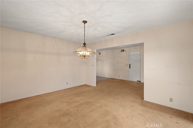 unfurnished room featuring a chandelier, carpet, and a textured ceiling