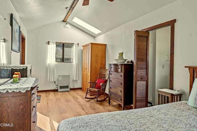 bedroom featuring ceiling fan, lofted ceiling with skylight, and light wood-type flooring