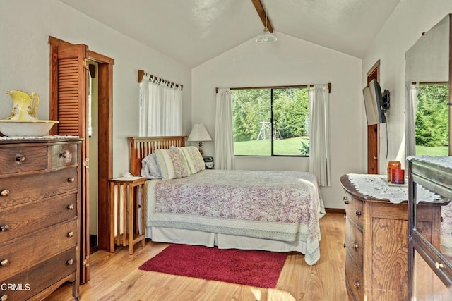 bedroom featuring multiple windows, lofted ceiling with beams, and light hardwood / wood-style floors