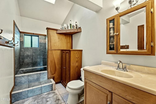 bathroom with lofted ceiling, tile patterned flooring, tiled shower, vanity, and toilet