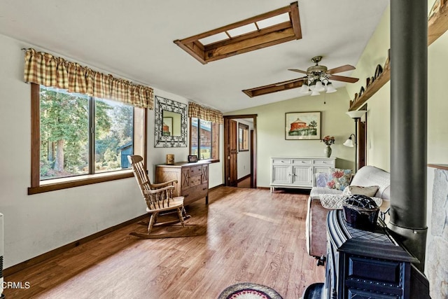 sitting room with wood-type flooring, lofted ceiling with skylight, and ceiling fan