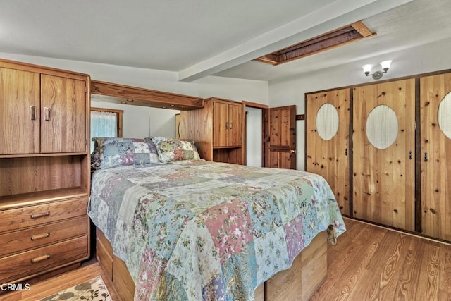 bedroom with beam ceiling and light hardwood / wood-style flooring