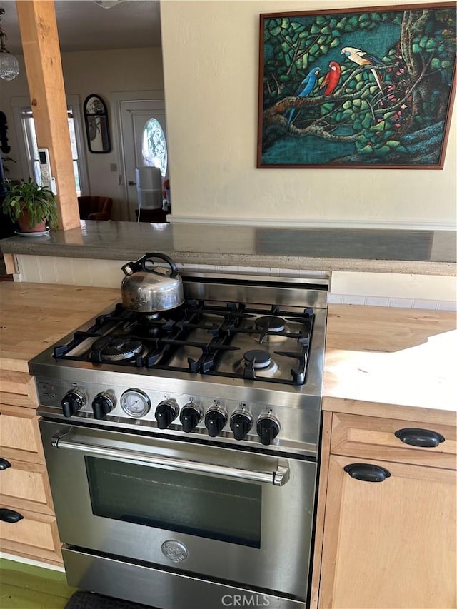 kitchen featuring light brown cabinetry, stainless steel stove, and butcher block counters