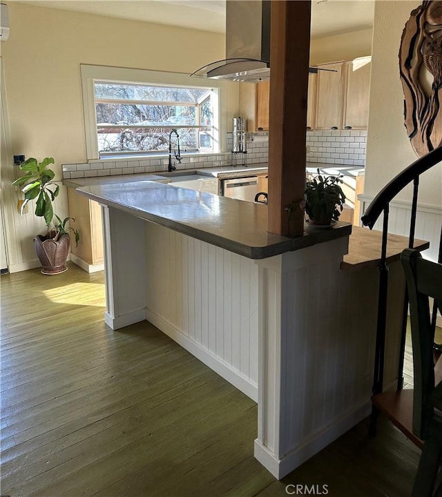 kitchen featuring island range hood, wood-type flooring, kitchen peninsula, and decorative backsplash