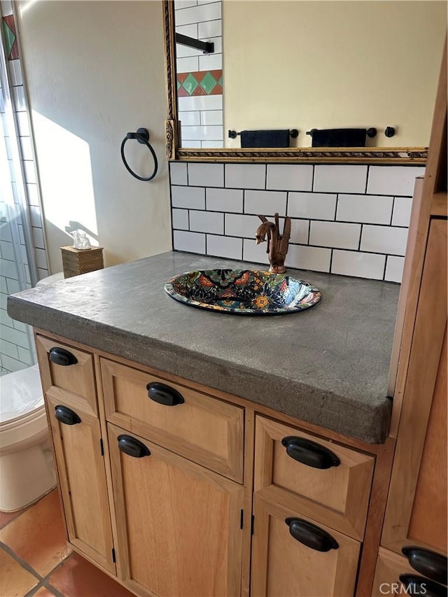 bathroom featuring vanity, toilet, and backsplash