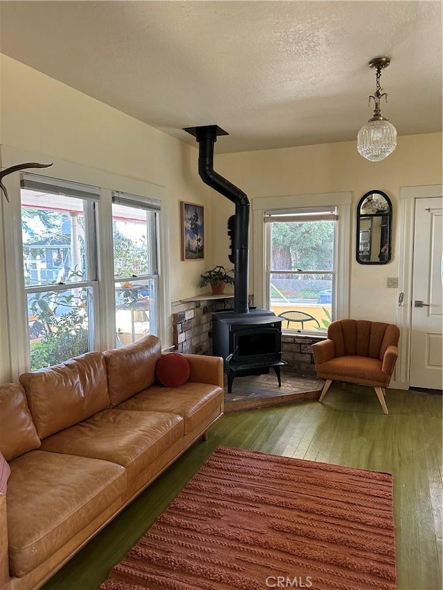 living room featuring a wealth of natural light, a wood stove, hardwood / wood-style floors, and a textured ceiling