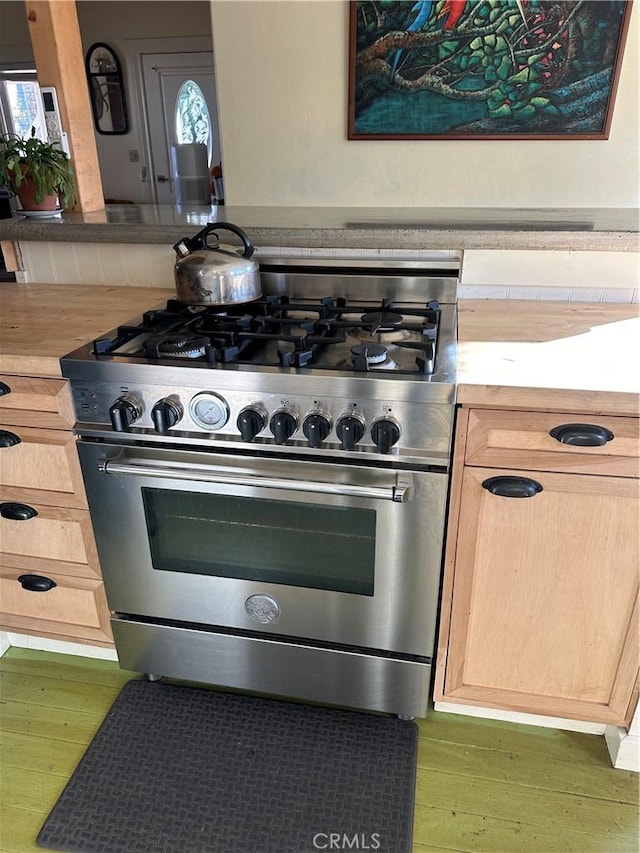 kitchen featuring dark wood-type flooring, stainless steel stove, and light brown cabinets