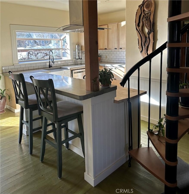 bar featuring hardwood / wood-style flooring, dishwasher, island range hood, light brown cabinetry, and decorative backsplash