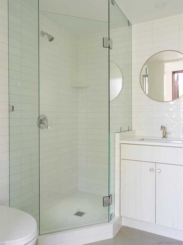 bathroom featuring vanity, toilet, an enclosed shower, and tile walls