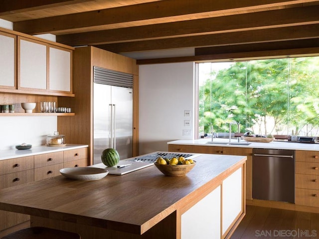 kitchen featuring appliances with stainless steel finishes, beamed ceiling, butcher block counters, sink, and dark hardwood / wood-style flooring