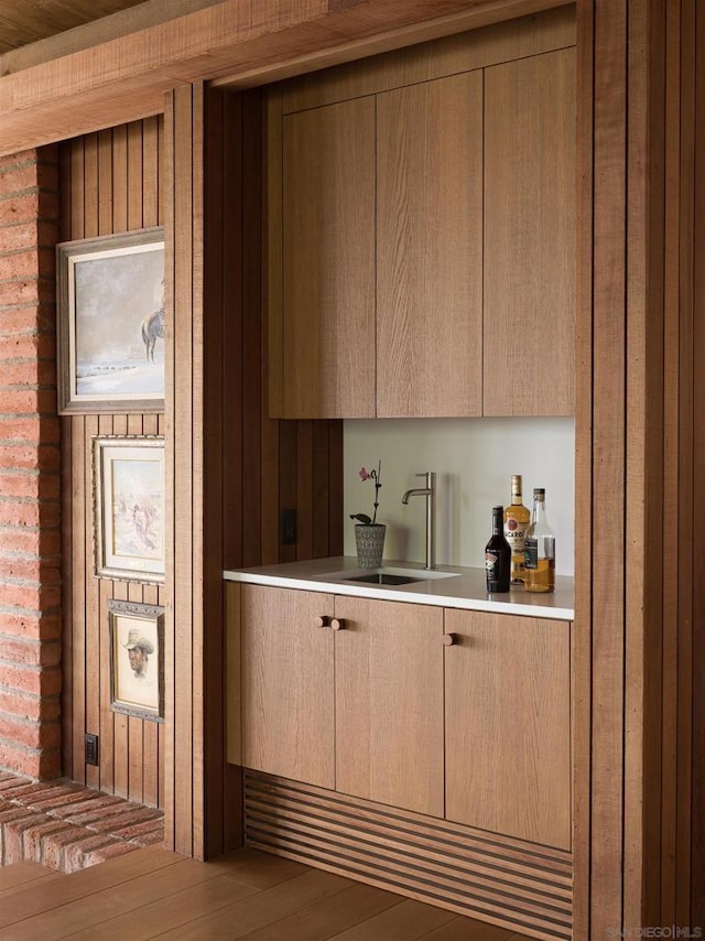 bar with hardwood / wood-style flooring and sink