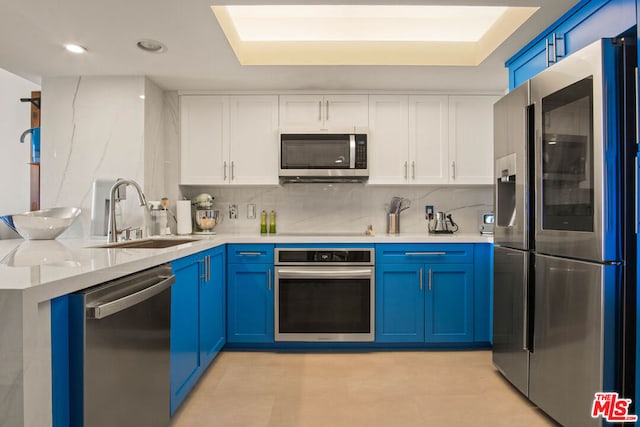 kitchen featuring white cabinetry, sink, stainless steel appliances, and blue cabinets