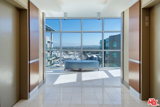 hallway featuring expansive windows, elevator, and light tile patterned floors