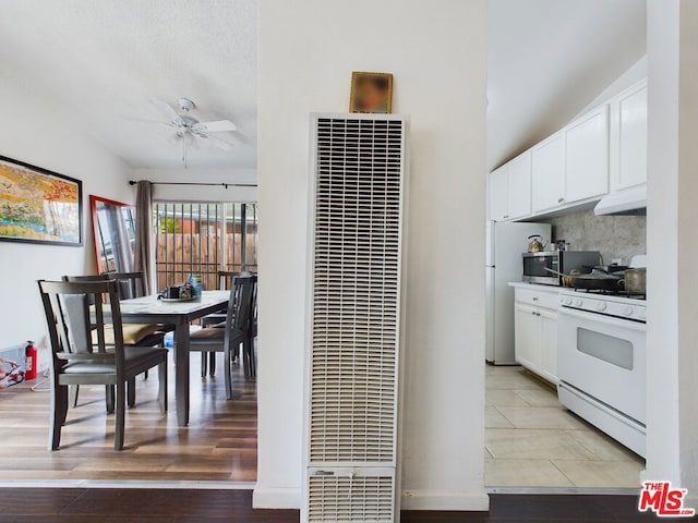 kitchen with white gas stove, white cabinets, ceiling fan, and light hardwood / wood-style floors