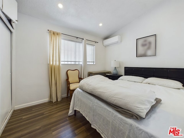 bedroom with dark wood-type flooring, lofted ceiling, a closet, and an AC wall unit