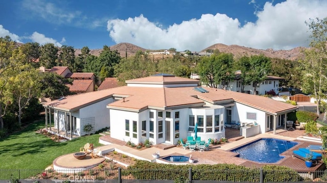 back of house featuring a sunroom, a fenced in pool, a patio, and a mountain view