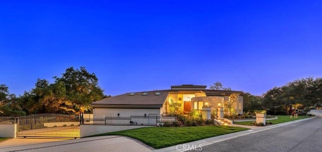 view of front of house with a garage, stucco siding, a fenced front yard, a gate, and a front yard