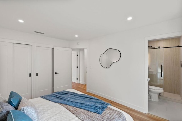 bedroom with connected bathroom and light hardwood / wood-style flooring