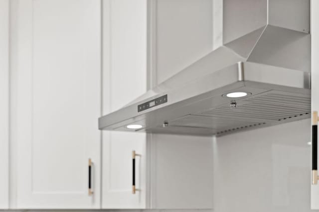 details featuring white cabinetry and wall chimney range hood