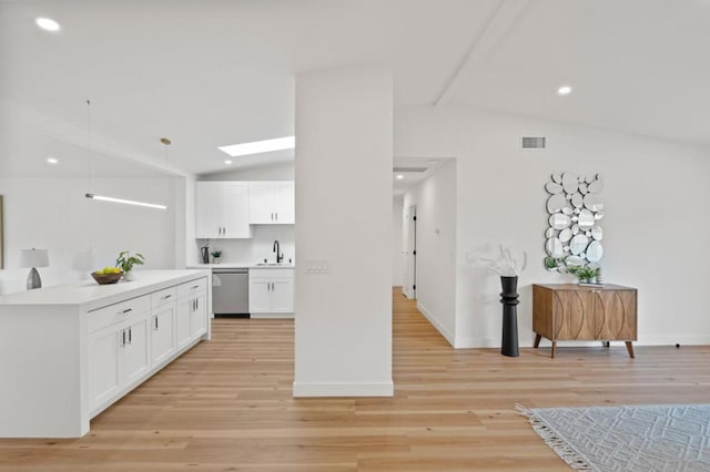 kitchen featuring vaulted ceiling with skylight, sink, white cabinets, hanging light fixtures, and stainless steel dishwasher