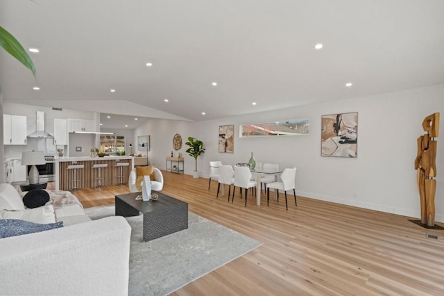 living room with light hardwood / wood-style flooring and vaulted ceiling