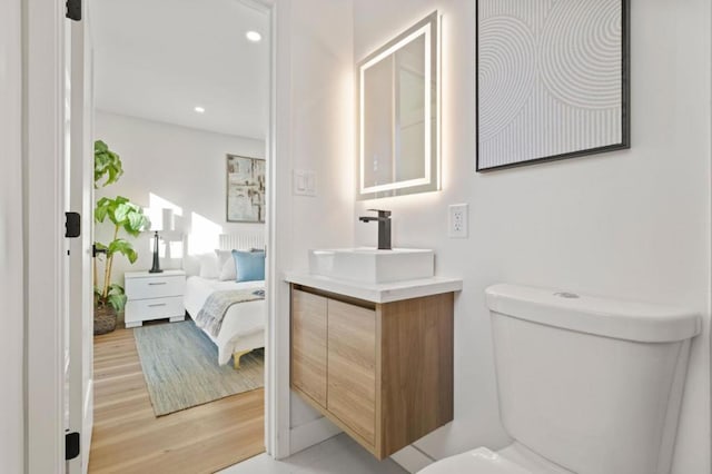 bathroom featuring wood-type flooring, toilet, and vanity