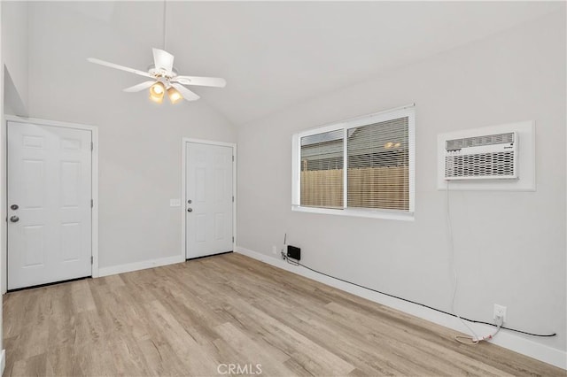 spare room with ceiling fan, high vaulted ceiling, a wall mounted air conditioner, and light wood-type flooring