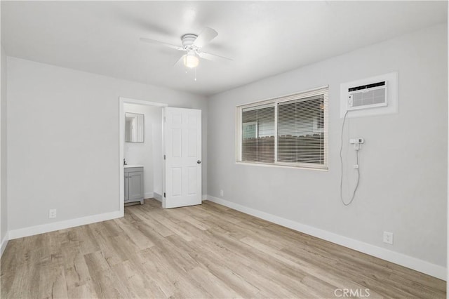 unfurnished bedroom featuring light hardwood / wood-style flooring, a wall unit AC, ceiling fan, and ensuite bathroom