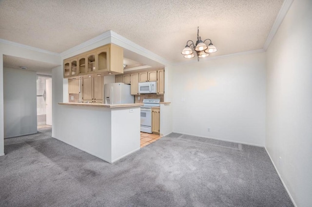 kitchen with white appliances, ornamental molding, light carpet, kitchen peninsula, and a chandelier