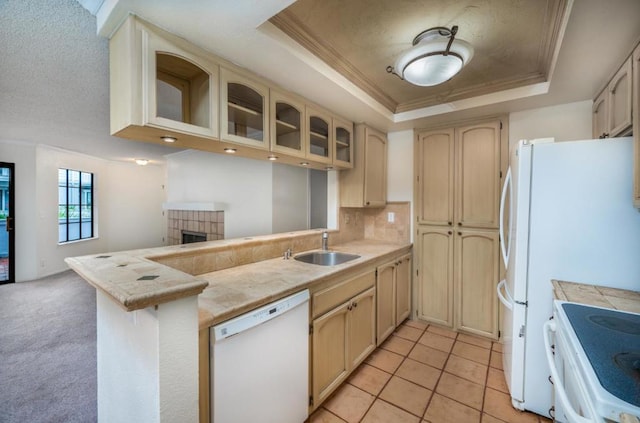 kitchen featuring a tray ceiling, sink, tile counters, kitchen peninsula, and white appliances