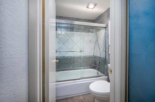 bathroom featuring combined bath / shower with glass door and toilet