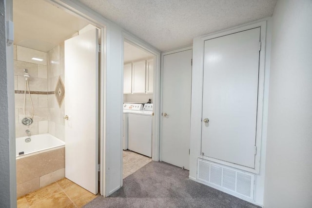 bathroom with tiled shower / bath, washer and dryer, and a textured ceiling