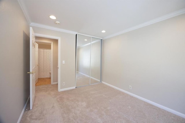 unfurnished bedroom with light carpet, ornamental molding, and a closet