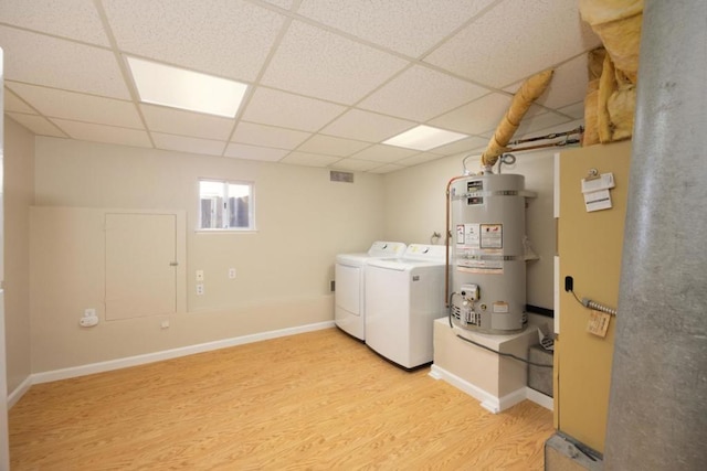 clothes washing area with secured water heater, independent washer and dryer, and light wood-type flooring