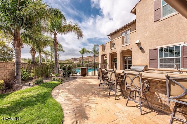 view of patio / terrace with a fenced in pool, grilling area, a wet bar, and exterior kitchen