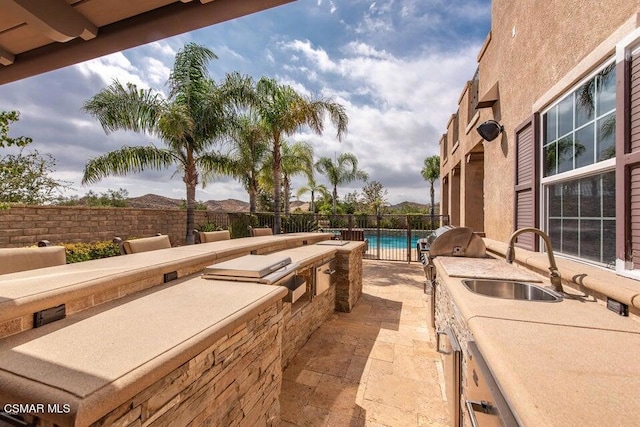 view of patio featuring exterior kitchen, an outdoor wet bar, and a fenced in pool