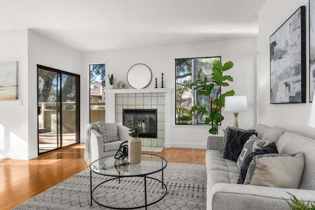 living room with a tiled fireplace and hardwood / wood-style flooring