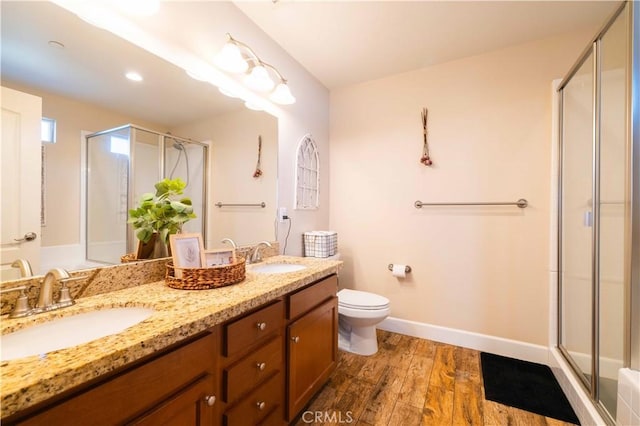 bathroom with hardwood / wood-style flooring, vanity, a shower with door, and toilet