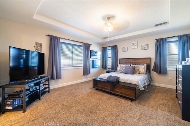 carpeted bedroom featuring a raised ceiling and ceiling fan