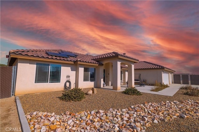 view of front of home with a garage, a patio area, and solar panels