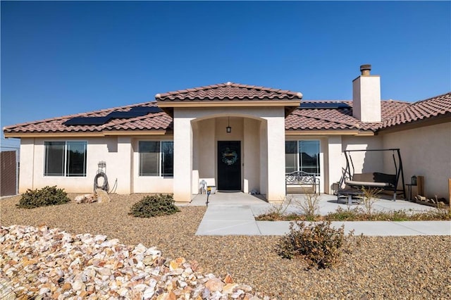 view of front of home with a patio and solar panels