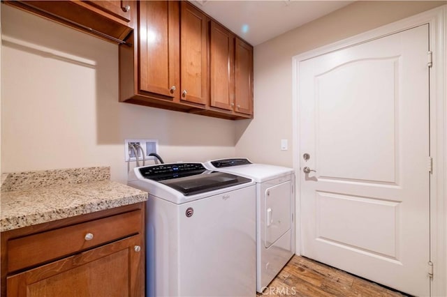 laundry room featuring separate washer and dryer, cabinets, and light wood-type flooring